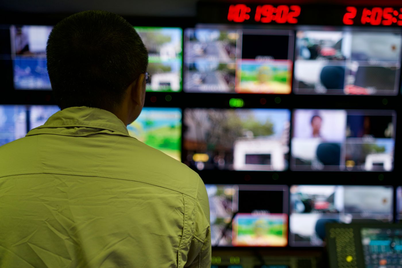Operator monitoring a wall of live camera feeds in a command centre